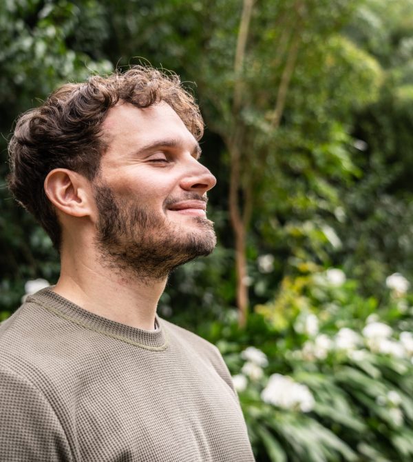 Mid adult man inhaling and breathing on nature background
